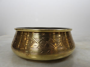⁠Front view of a vintage handcrafted brass bowl with traditional hand-engraved geometric patterns around the side, polished golden patina, on a light marble background