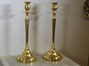 Pair of tall 20-inch solid brass candlesticks standing on marble surface, elegant vintage brass candle holders set for dining table decoration